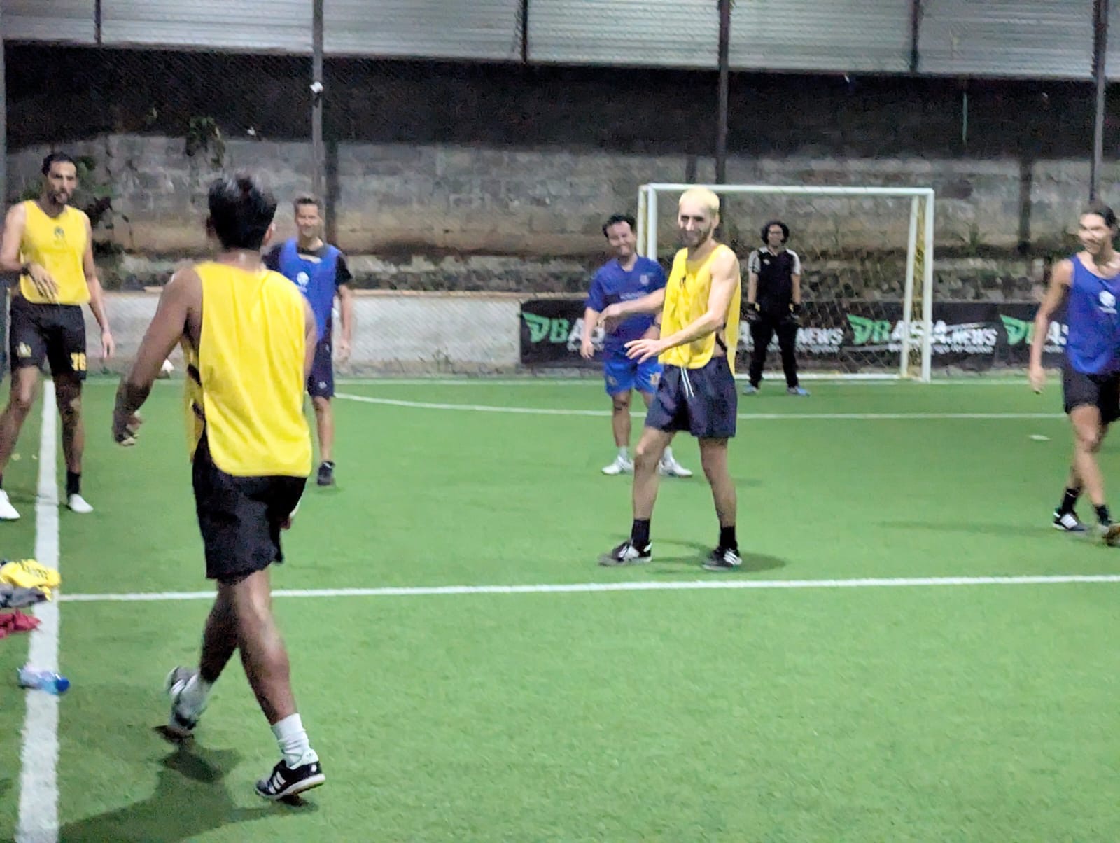Players in yellow bibs during a night training match